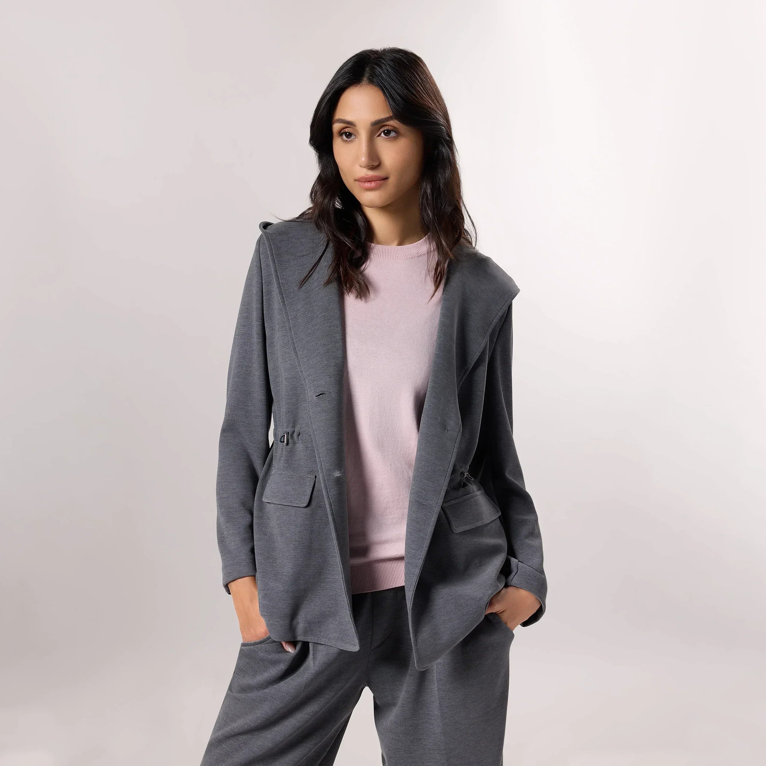 A model wearing seasonal grey hooded blazer - عارضة أزياء ترتدي سترة رمادية بغطاء رأس