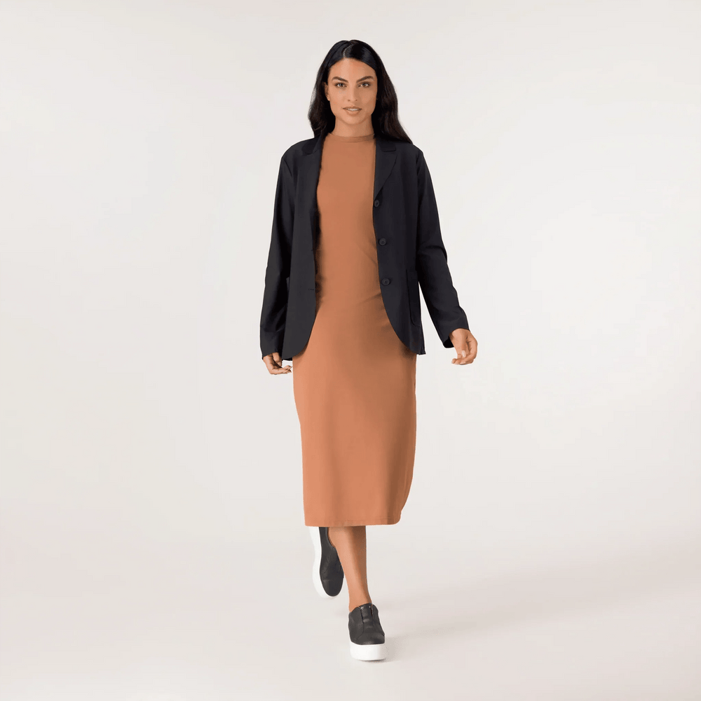 A model wearing a seasonal black light blazer over a brown dress - عارضة أزياء ترتدي سترة سوداء خفيفة فوق فستان بني