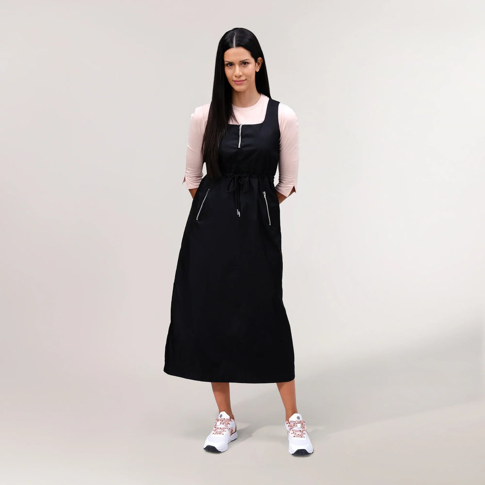 Black pinafore dress with structured fit & front zipper - عارضة أزياء ترتدي فستان "بينا فور" باللون الأسود يتميّز بسحّاب أمامي وقصّة أنيقة