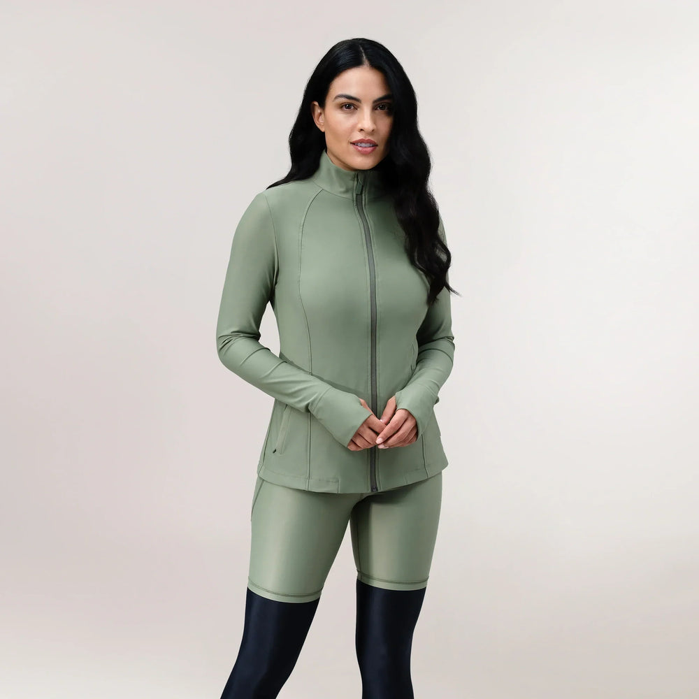 A model wearing core green glide active jacket & short - عارضة أزياء ترتدي سترة رياضية باللون الأخضر مع شورت قصير متناسق