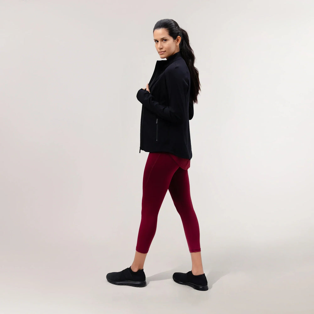 A model wearing a core black sculpting jacket over maroon leggings - عارضة أزياء ترتدي سترة مجسمة سوداء اللون فوق ليقنز كستنائي اللون