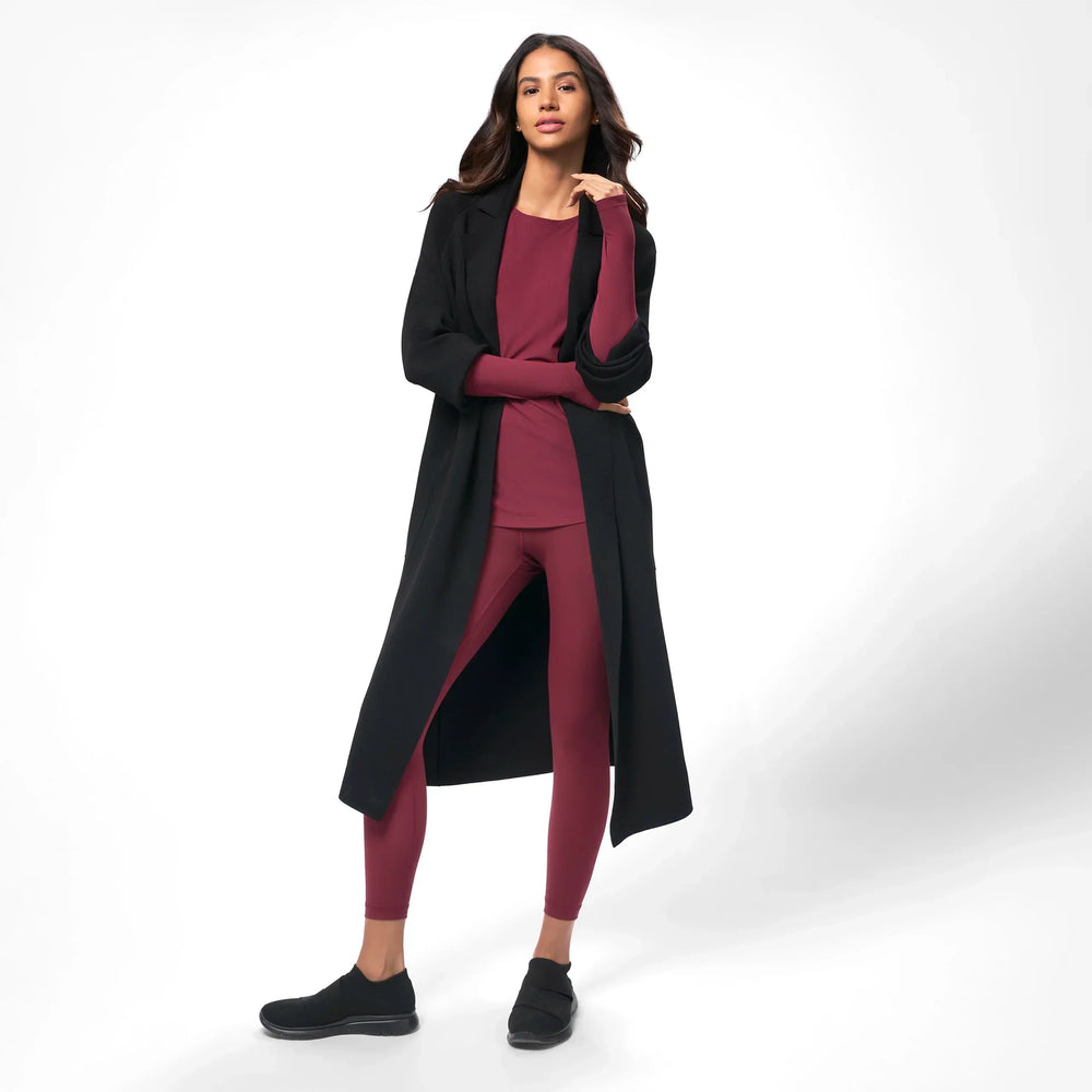 A model in seasonal black full length knitted coat over maroon set - عارضة أزياء ترتدي معطف طويل محبوك باللون الأسود فوق طقم نبيتى اللون