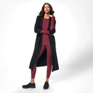 A model in seasonal black full length knitted coat over maroon set - عارضة أزياء ترتدي معطف طويل محبوك باللون الأسود فوق طقم نبيتى اللون