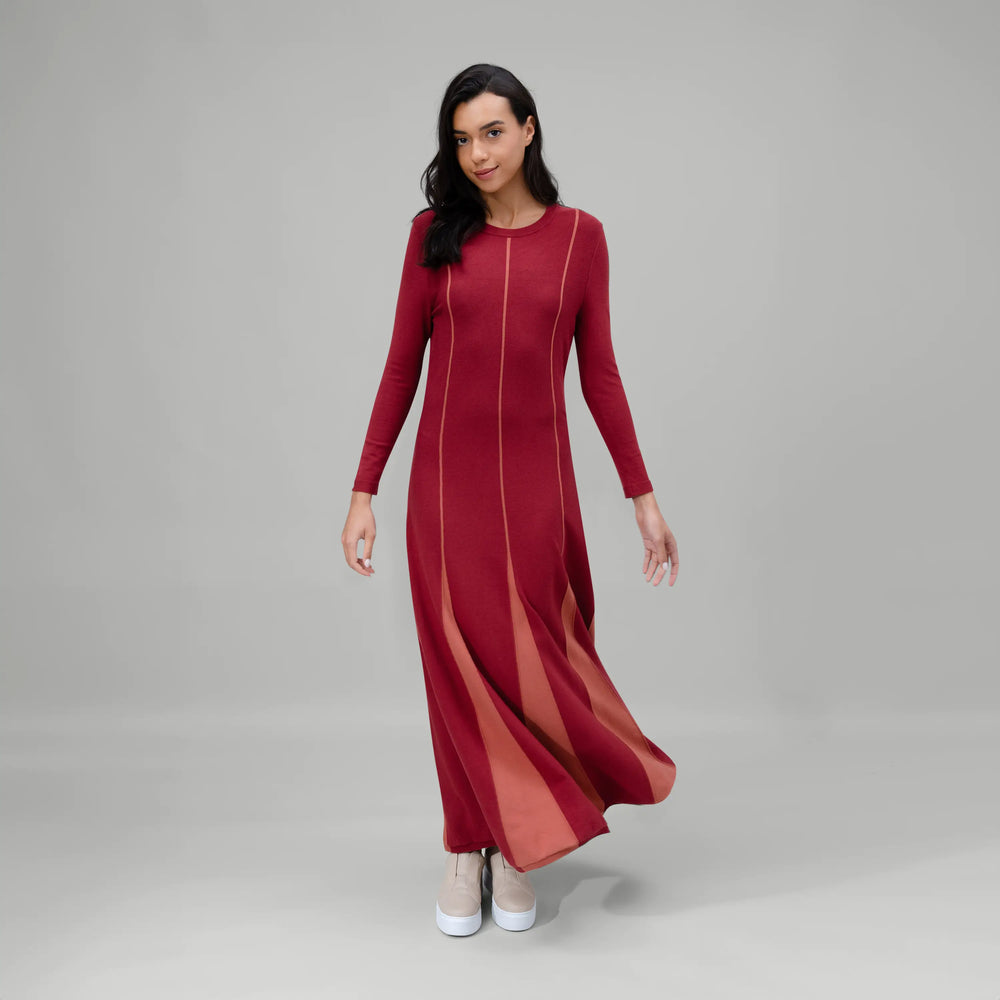 A model wearing grape red panel dress with flared hem - عارضة أزياء ترتدي فستان بقطع تصميمية باللون الأحمر العنابي وحافة واسعة