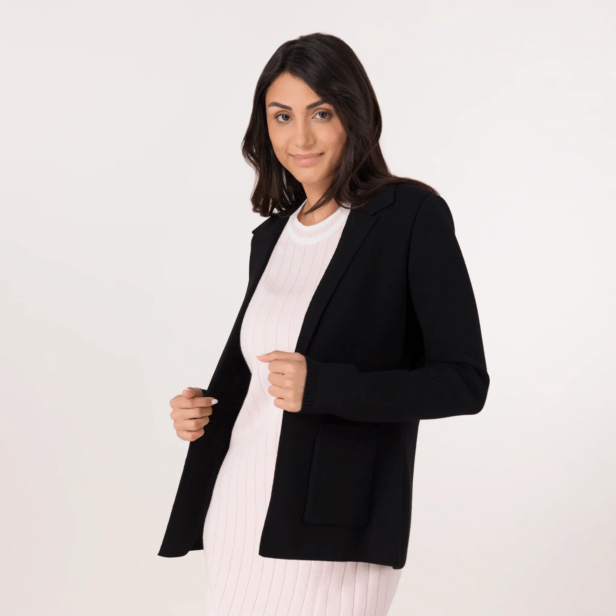 A model wearing seasonal black knitted blazer over a white dress - عارضة أزياء ترتدي سترة سوداء محبوكة فوق فستان أبيض
