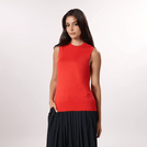 A model in seasonal red knitted tank sweater over black pleated skirt - عارضة أزياء ترتدي توب محبوك بدون أكمام باللون الأحمر الموسمي فوق تنورة سوداء مطوية
