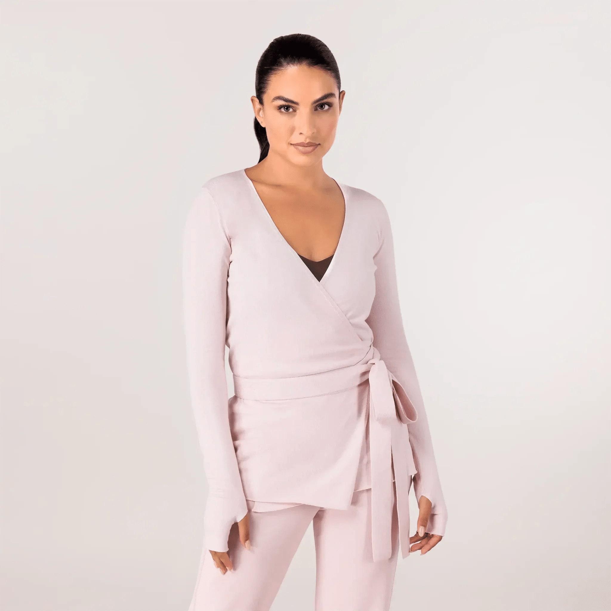 A model wearing a core light pink wrap sweater - عارضة أزياء ترتدي سترة ملفوفة باللون الوردي الفاتح