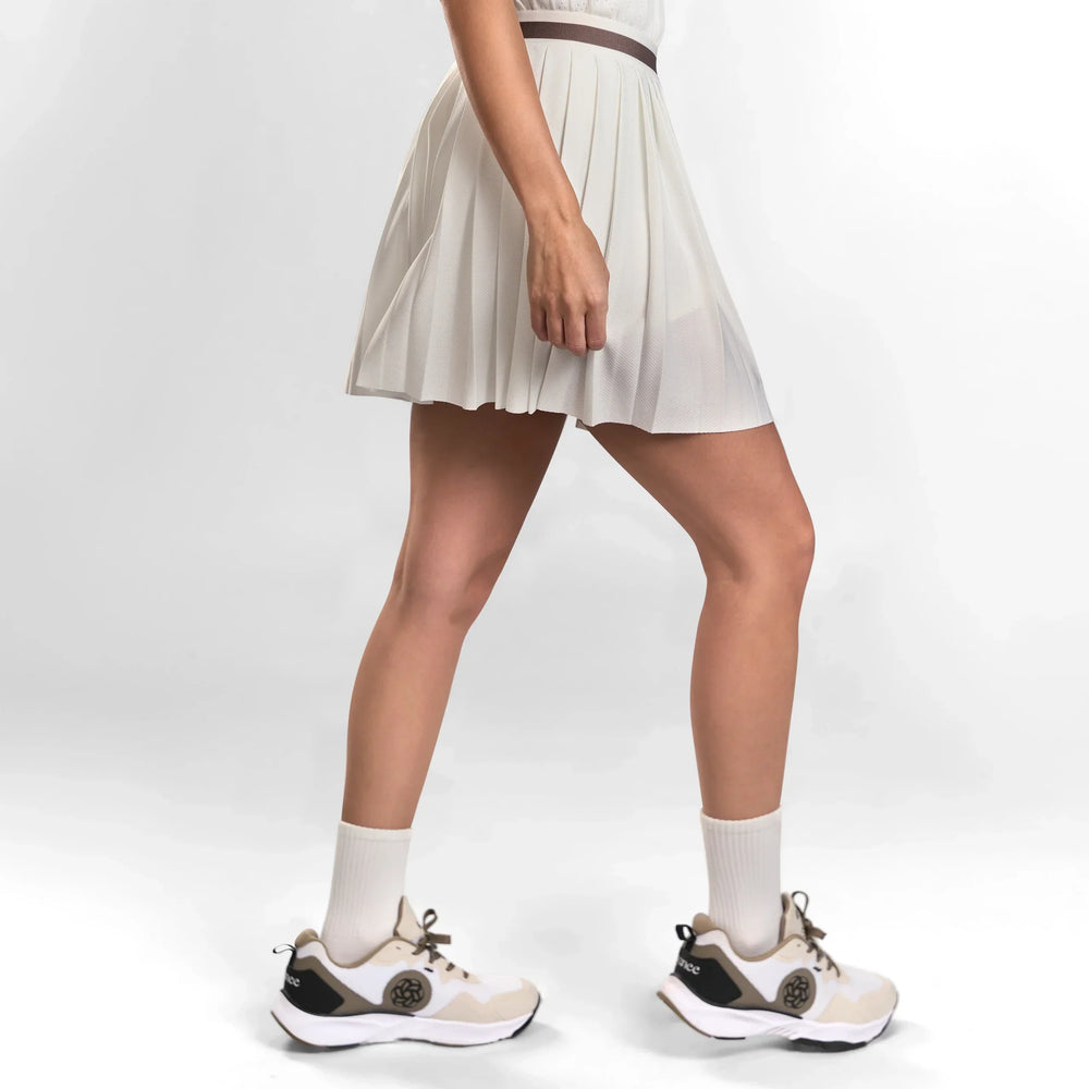 A model wearing short seasonal white pleated skirt with sneakers - عارضة أزياء ترتدي تنورة قصيرة بيضاء بثنيات مع حذاء رياضي