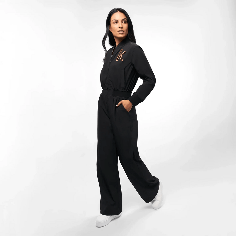 A model in a seasonal black utility jumpsuit with Kayanee's first initial on it - عارضة أزياء ترتدي جمبسوت سوداء مع الحرف الأول من اسم كياني عليها