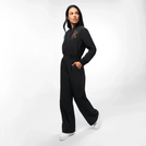 A model in a seasonal black utility jumpsuit with Kayanee's first initial on it - عارضة أزياء ترتدي جمبسوت سوداء مع الحرف الأول من اسم كياني عليها
