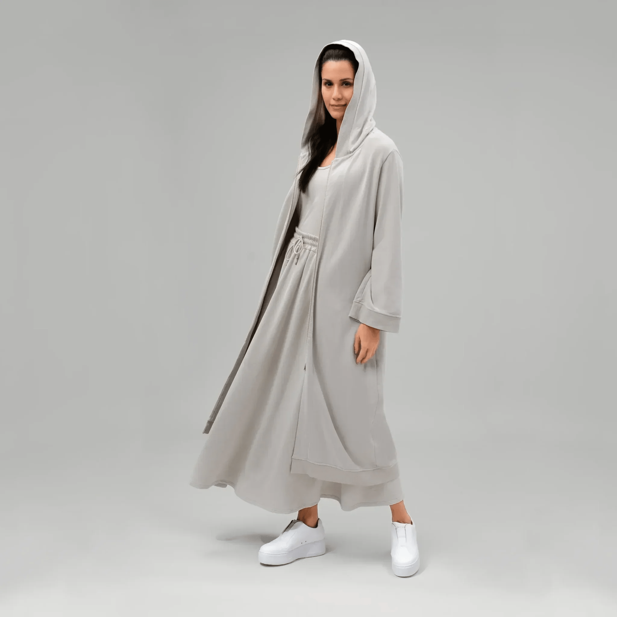 A model wearing core stone hooded good to go abaya - عارضة أزياء ترتدي عباءة بغطاء رأس باللون الحجري