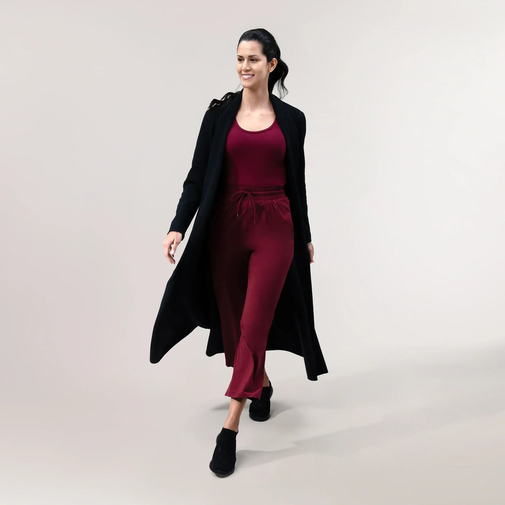 A model wearing a core black weekday coat over a maroon set - عارضة أزياء ترتدي معطف أسود يومي فوق طقم نبيتى اللون
