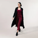 A model wearing a core black weekday coat over a maroon set - عارضة أزياء ترتدي معطف أسود يومي فوق طقم نبيتى اللون