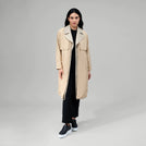 A model in seasonal beige gilet hybrid two piece trench coat - عارضة أزياء ترتدي معطف ترينش مكون من قطعتين باللون البيج