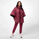 A model wearing seasonal burgundy puffer cape over a matching set - عارضة أزياء ترتدي كاب مبطّن باللون العنابي الموسمي فوق طقم متناسق