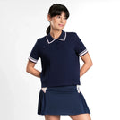 A model wearing a seasonal navy pointelle polo over a short skirt - عارضة أزياء ترتدي تيشيرت بولو أزرق داكن اللون فوق تنورة قصيرة