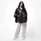 A model wearing a core black reversible cape over grey pants - عارضة أزياء ترتدي كاب قصير شتوي أسود بوجهين فوق بنطال رمادي