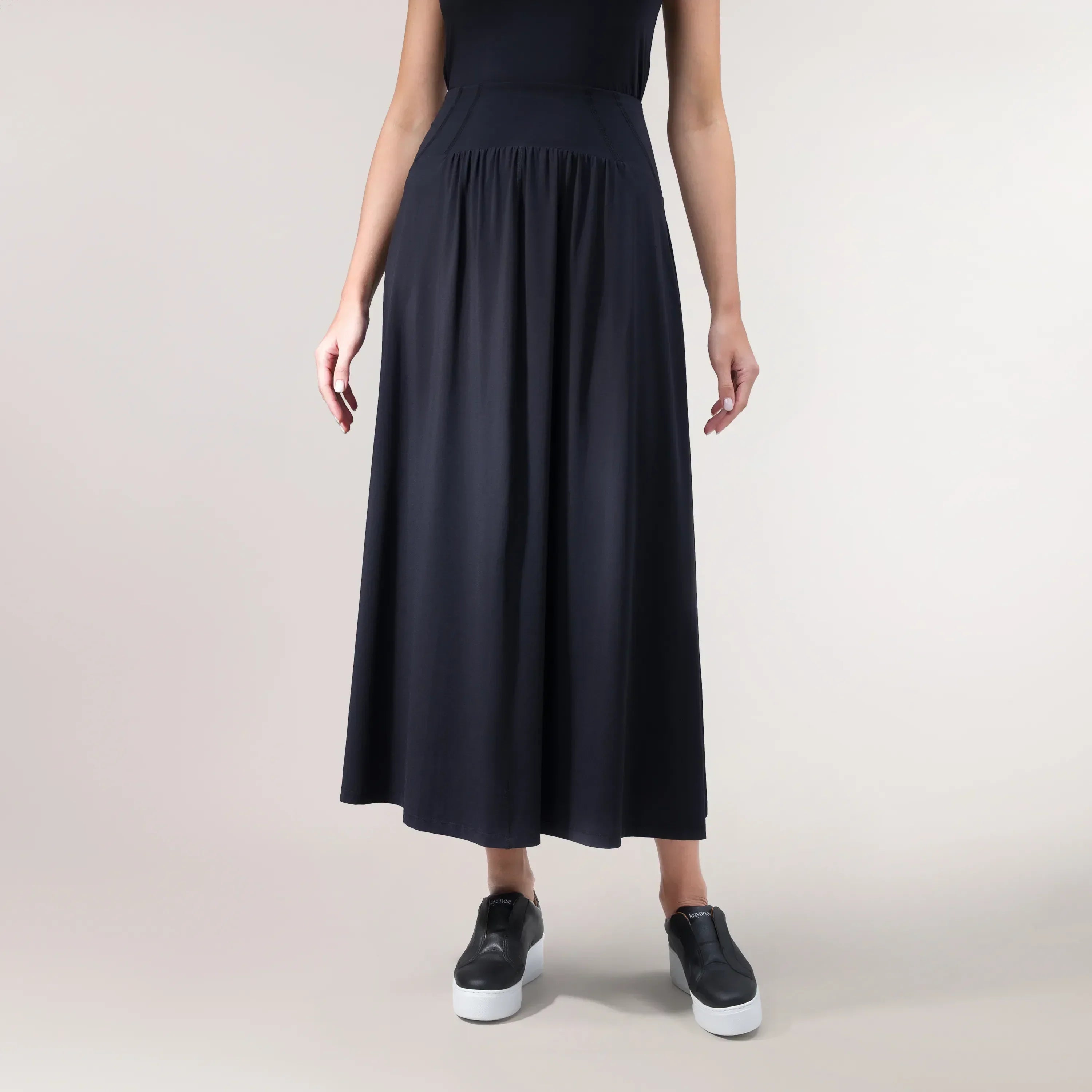 A model wearing a black "Flow" jersey techno skirt with an athletic cut - عارضة أزياء ترتدي تنورة "فلو" من قماش الجيرسي باللون الأسود وبقصّة رياضية