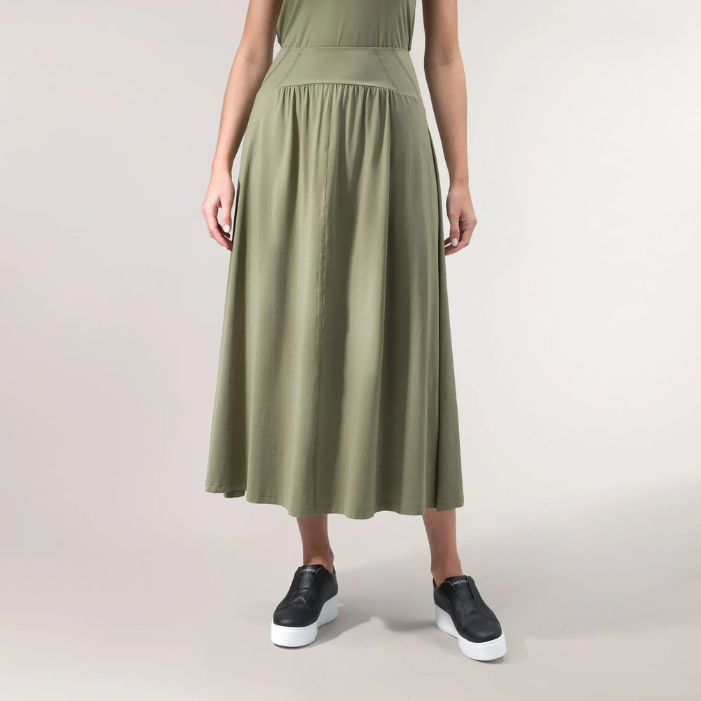 A model wearing a core musk green Flow jersey techno skirt - عارضة أزياء ترتدي تنورة "فلو" من القماش الجيرسي التكنولوجي باللون الأخضر