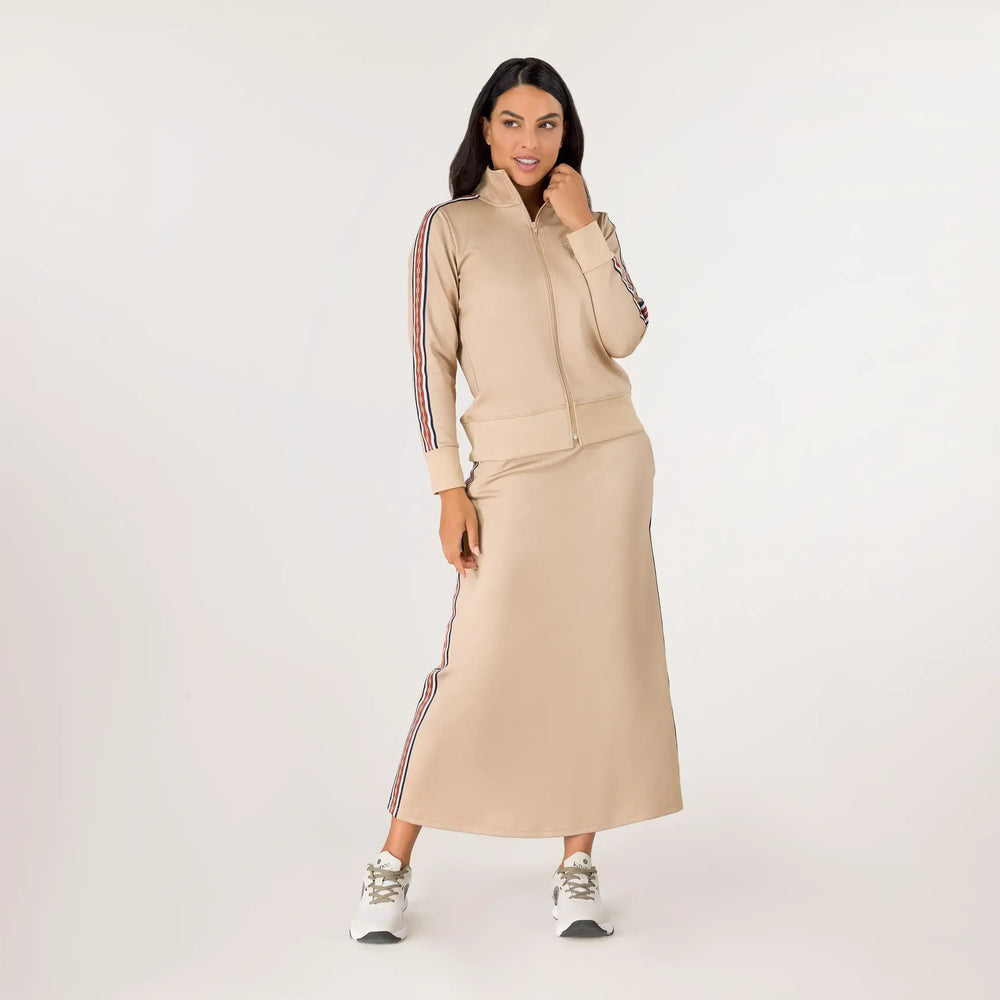 A model wearing a seasonal sand midi track skirt set with striped ines - عارضة أزياء ترتدي تنورة رياضية متوسطة الطول باللون الرملي ذات خطوط جانبية