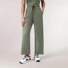 A model wearing a core musk green Flow lounge pants with side pockets - عارضة أزياء ترتدي بنطلون "فلو" مريح باللون الأخضر مع جيوب جانبية