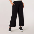 A model wearing black flared track pants with a relaxed athletic fit - عارضة أزياء ترتدي بنطال رياضي أسود واسع بقصّة رياضية مريحة