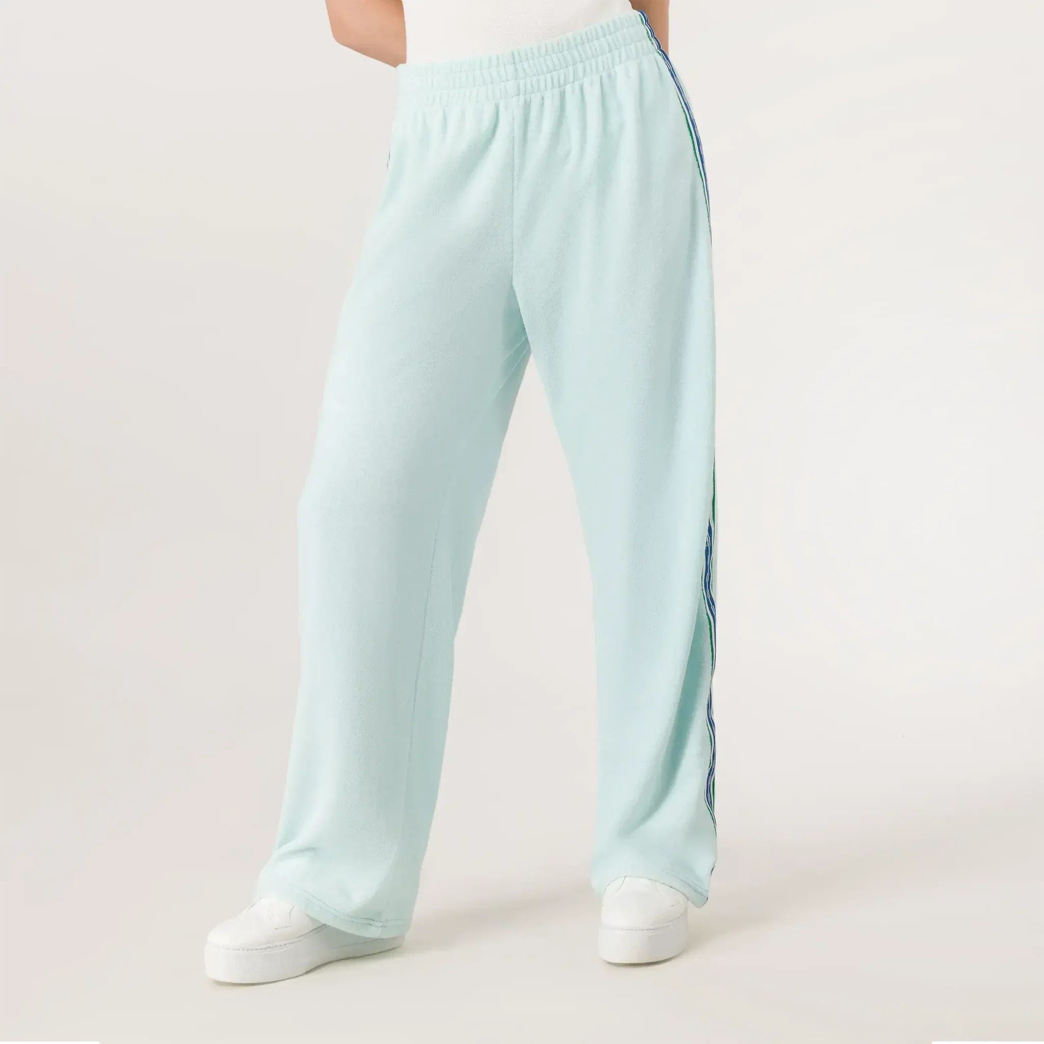 A model wearing a seasonal light blue velour track pants with side stripes - عارضة أزياء ترتدي بنطال رياضي باللون الأزرق فاتح مع خطوط جانبية