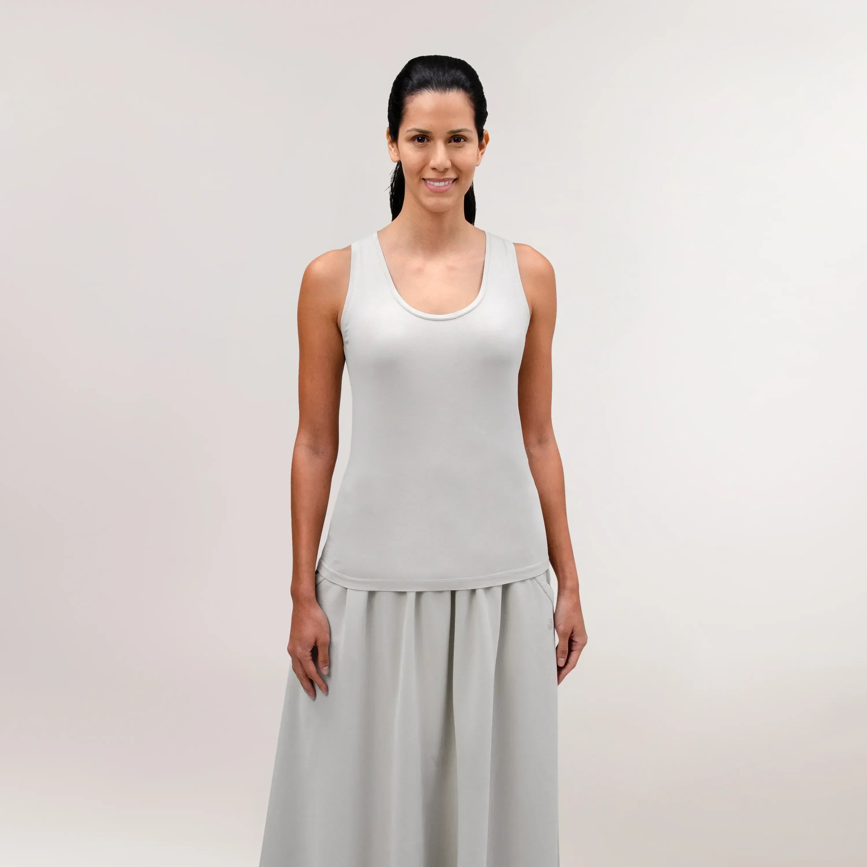 A model wearing a core stone tank top over a matching skirt - عارضة أزياء ترتدي قميص باللون الحجري فوق تنورة متناسقة