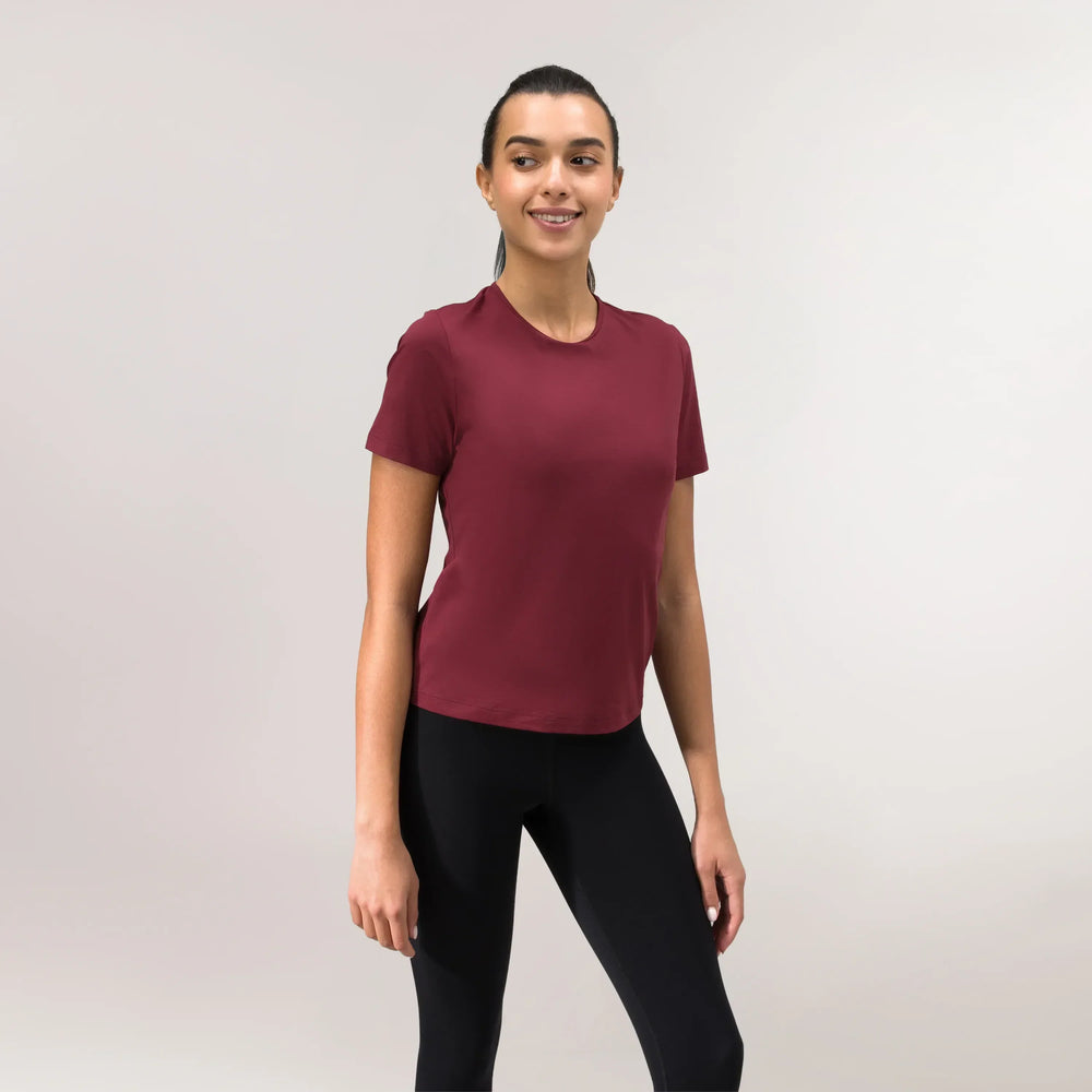 A model wearing a core grape red Flow top over black leggings - عارضة أزياء ترتدي بلوزة "فلو" باللون الأحمر فوق ليقنز أسود