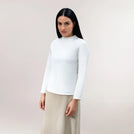 A model wearing a soft white long-sleeve tee with a relaxed seasonal fit - عارضة أزياء ترتدي تيشيرت أبيض ناعم بأكمام طويلة وقصّة موسمية مريحة