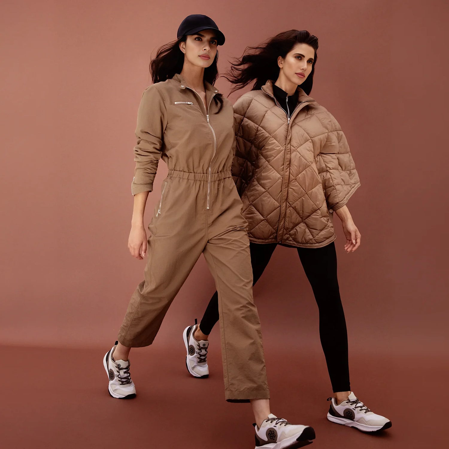 Two girls, one in a jumpsuit and the other in sport pants with a jacket, available at Kayanee KSA