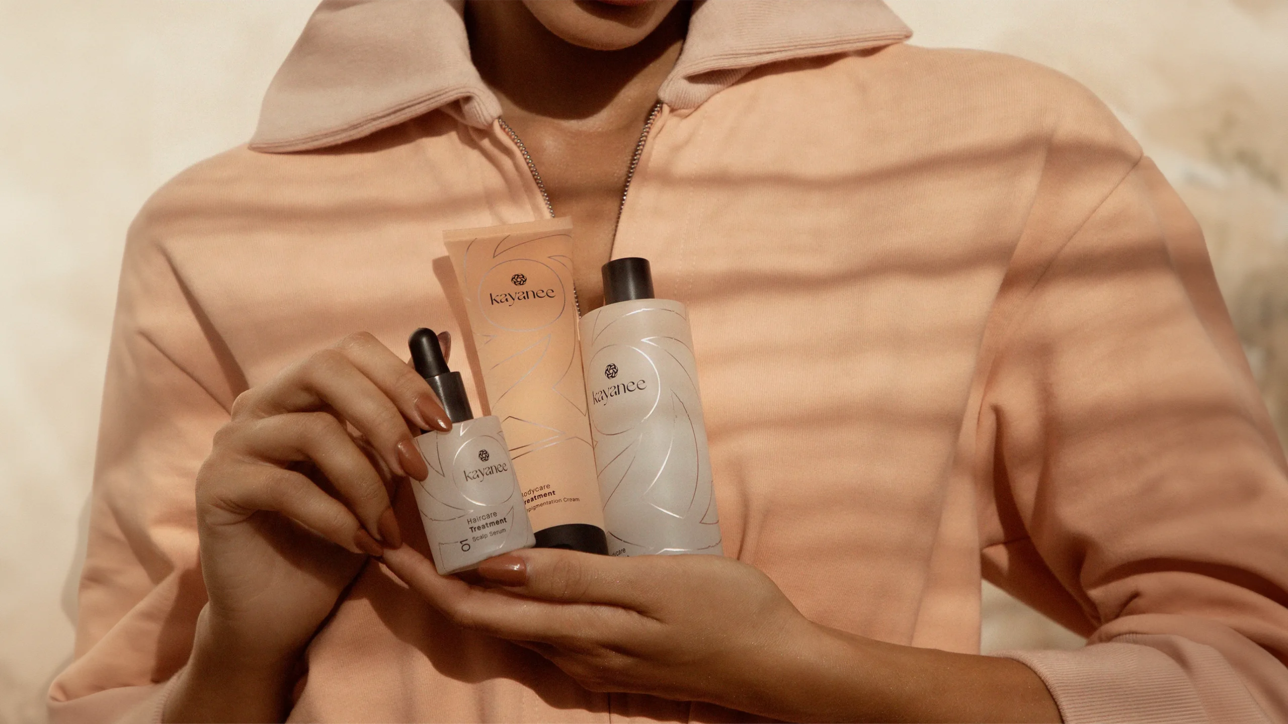 A girl holding hair and body care products from the Kayanee Restore Collection