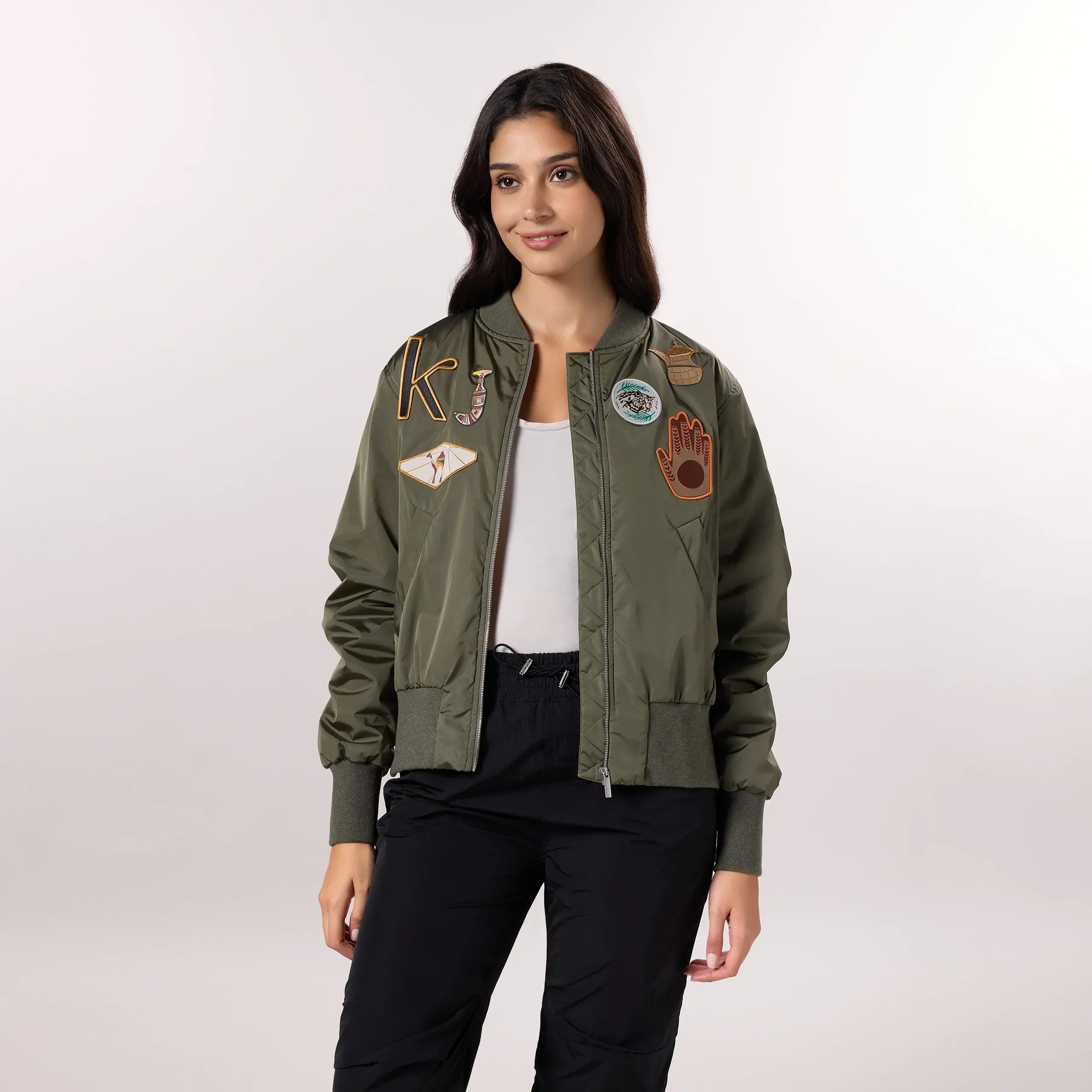 A model wearing seasonal olive bomber jacket with trendy badges - عارضة أزياء ترتدي سترة باللون الزيتي ذات شارات عصرية