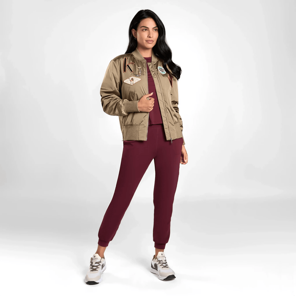 A model in seasonal brown bomber jacket with badges over a red suit - عارضة أزياء ترتدي سترة بنية اللون مع شارات فوق بدلة حمراء