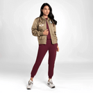 A model in seasonal brown bomber jacket with badges over a red suit - عارضة أزياء ترتدي سترة بنية اللون مع شارات فوق بدلة حمراء