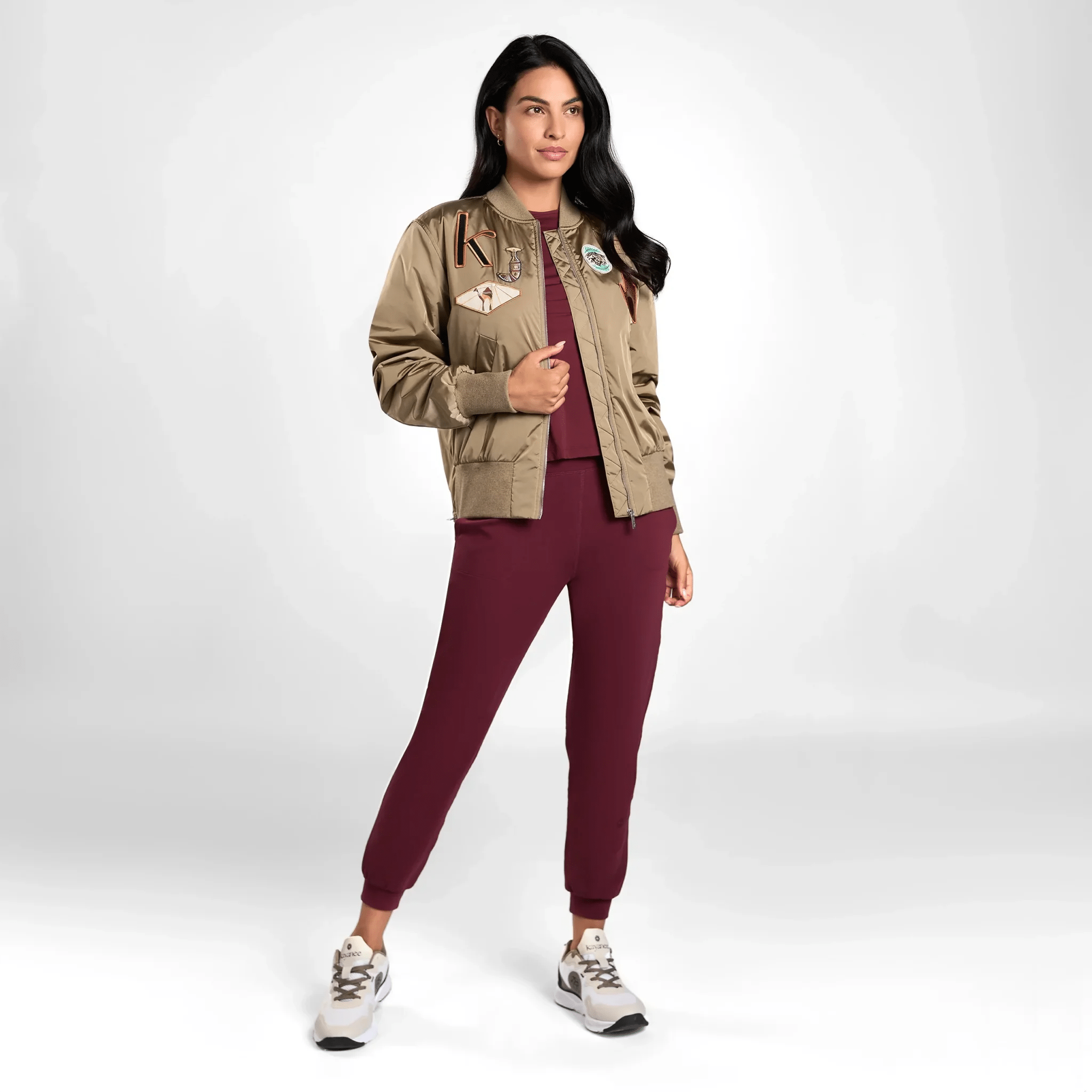 A model in seasonal brown bomber jacket with badges over a red suit - عارضة أزياء ترتدي سترة بنية اللون مع شارات فوق بدلة حمراء