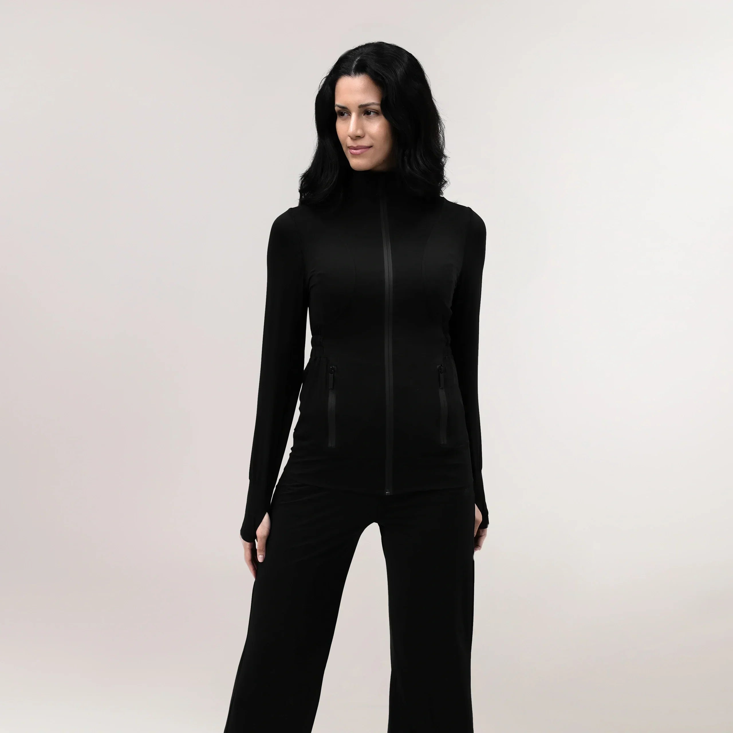 A model wearing a black "Flow" active jacket with a zipped front - عارضة أزياء ترتدي جاكيت رياضي "فلو" باللون الأسود مع سحاب أمامي