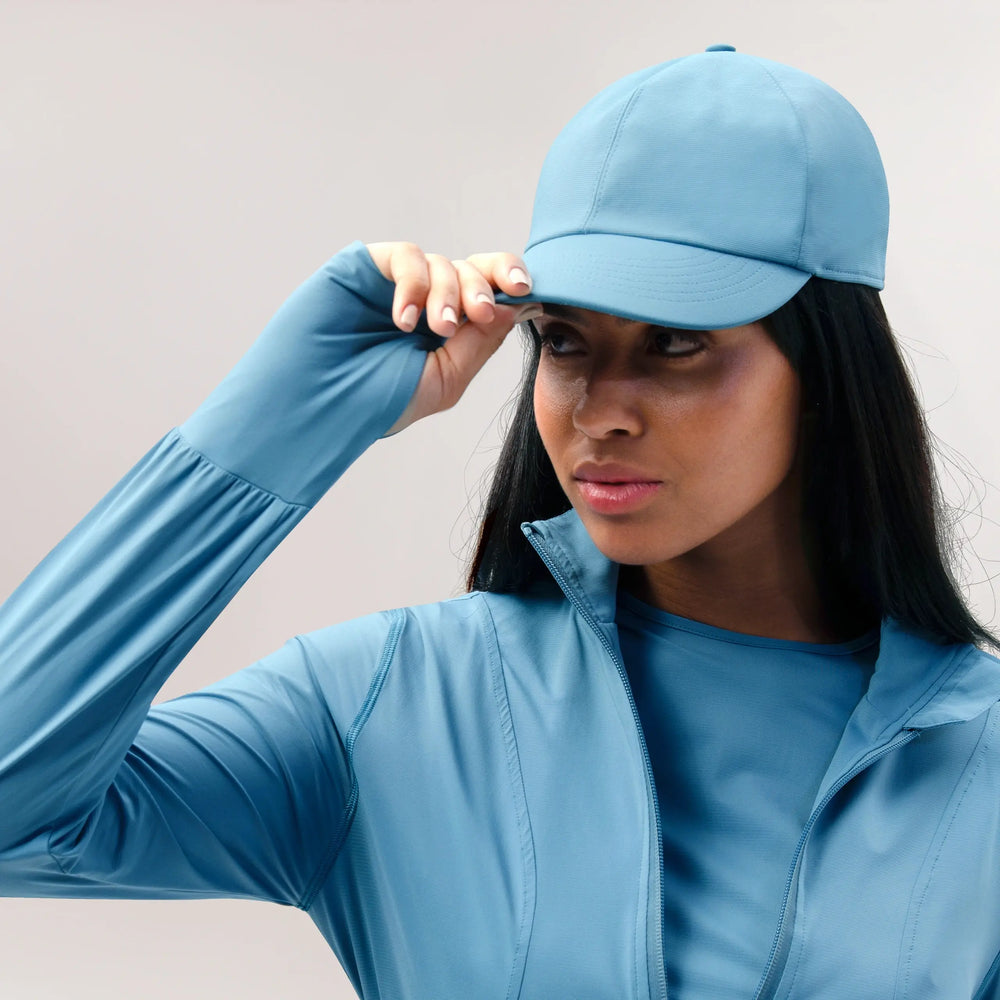 A model wearing a core blue baseball cap - عارضة أزياء ترتدي قبعة بيسبول زرقاء اللون