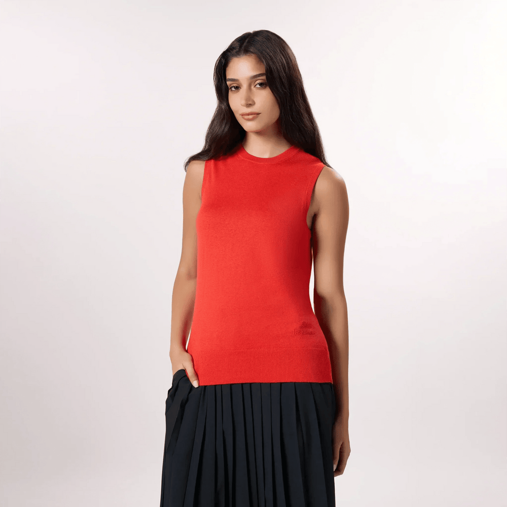A model in seasonal red knitted tank sweater over black pleated skirt - عارضة أزياء ترتدي توب محبوك بدون أكمام باللون الأحمر الموسمي فوق تنورة سوداء مطوية