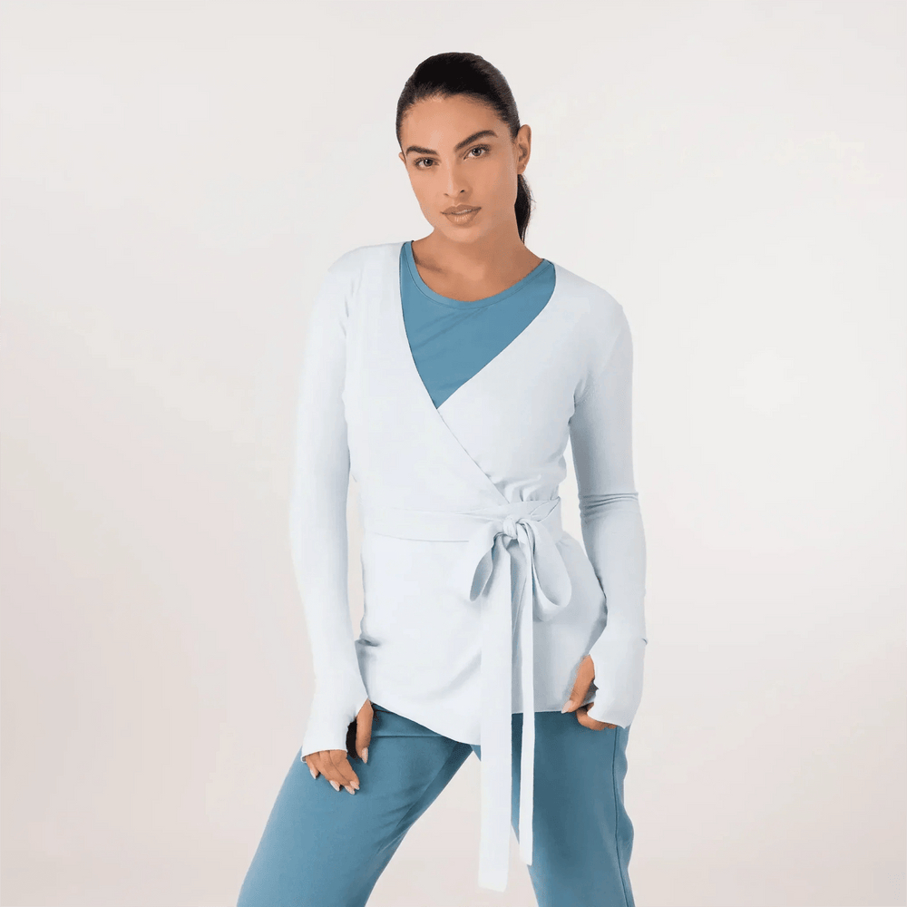 A model in light blue wrap sweater over teal pants - عارضة أزياء ترتدي سترة بقصة مميزة باللون الأزرق الفاتح فوق بنطلون أزرق مخضر