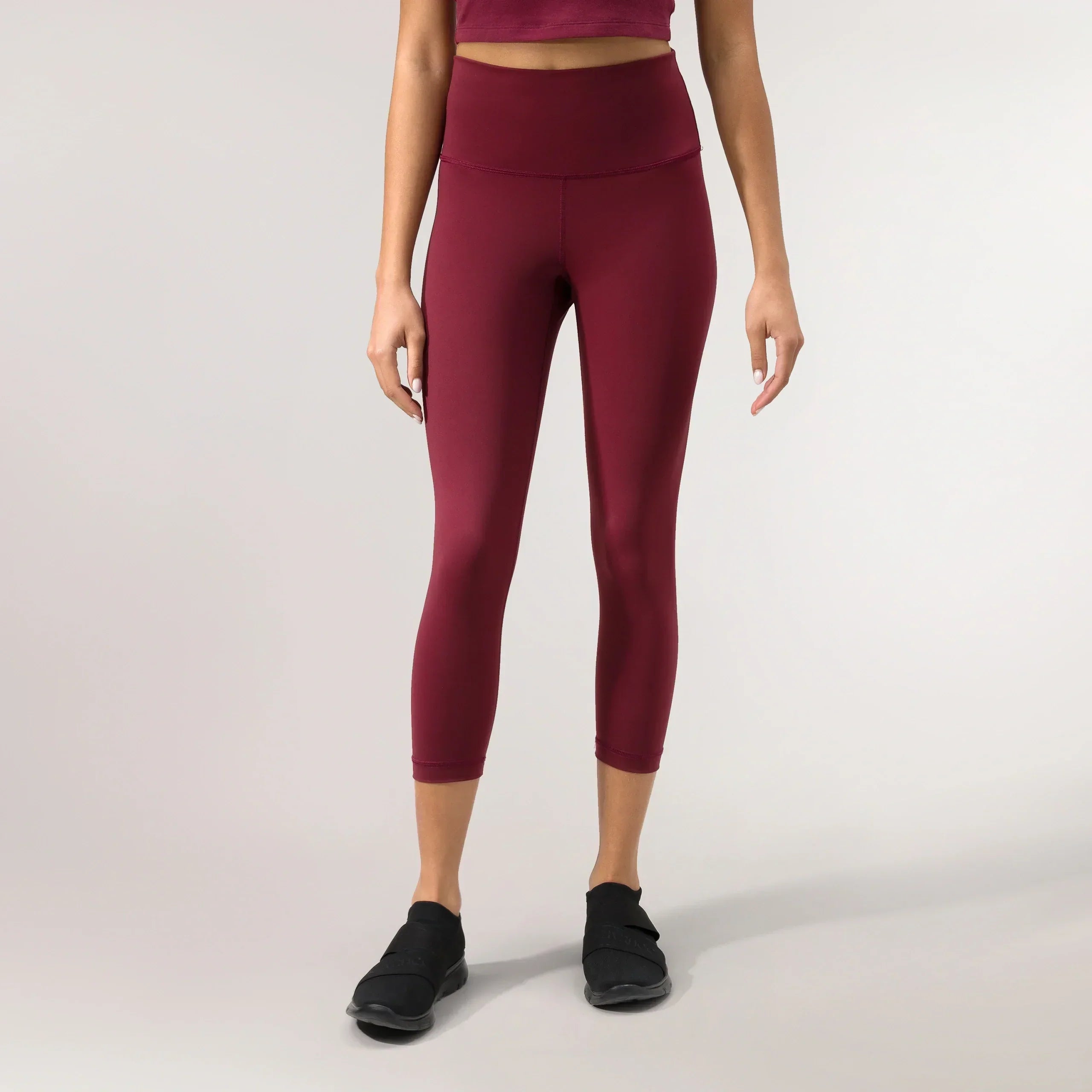 A model wearing grape red compression crop leggings with sculpting fit - عارضة أزياء ترتدي ليغينغ ضاغط قصير باللون الأحمر العنابي بقصة تنحت القوام