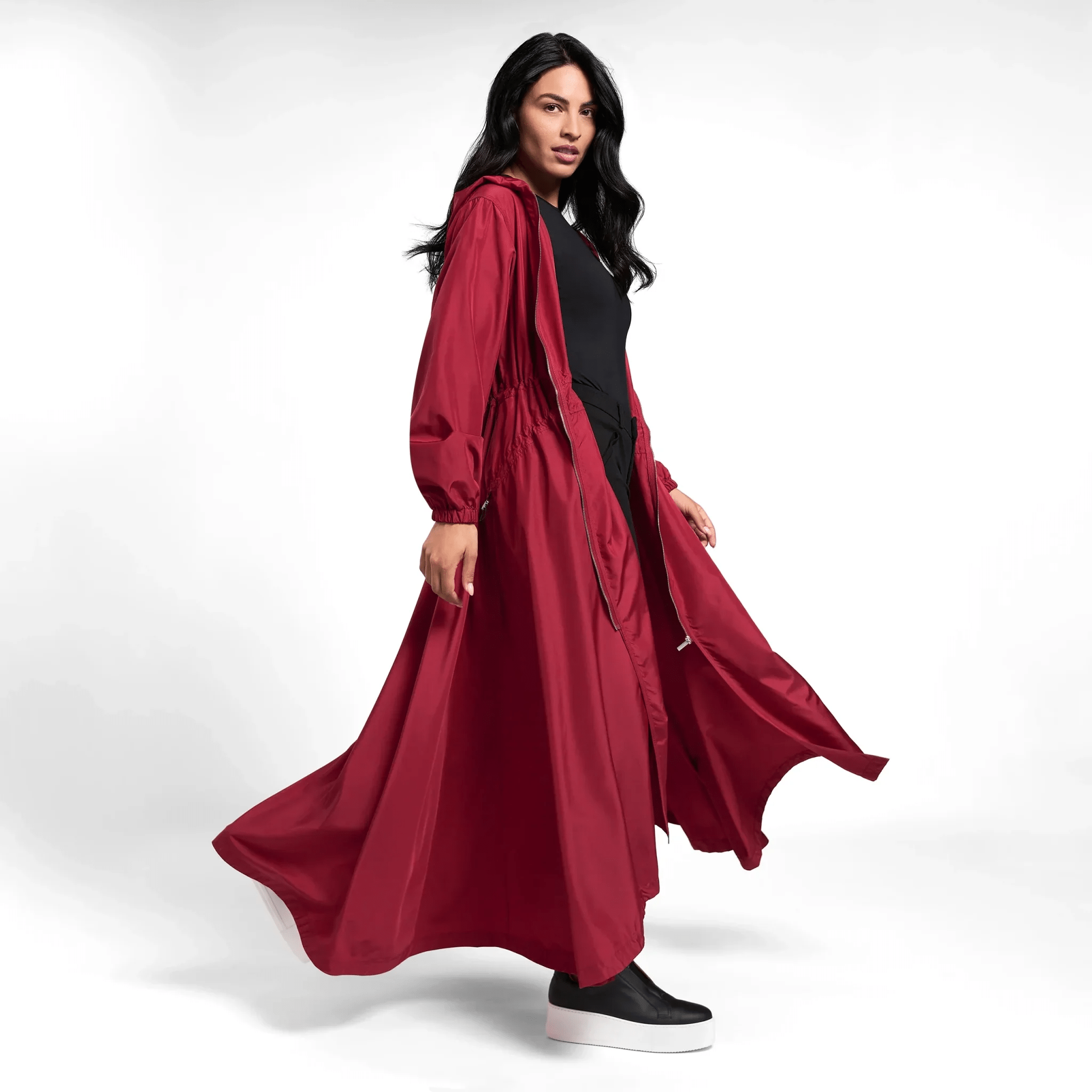 A model in a seasonal dark red hooded parka with adjustable waist band - عارضة أزياء ترتدي سترة باركا حمراء داكنة تتميز بحزام قابل للتعديل وغطاء رأس