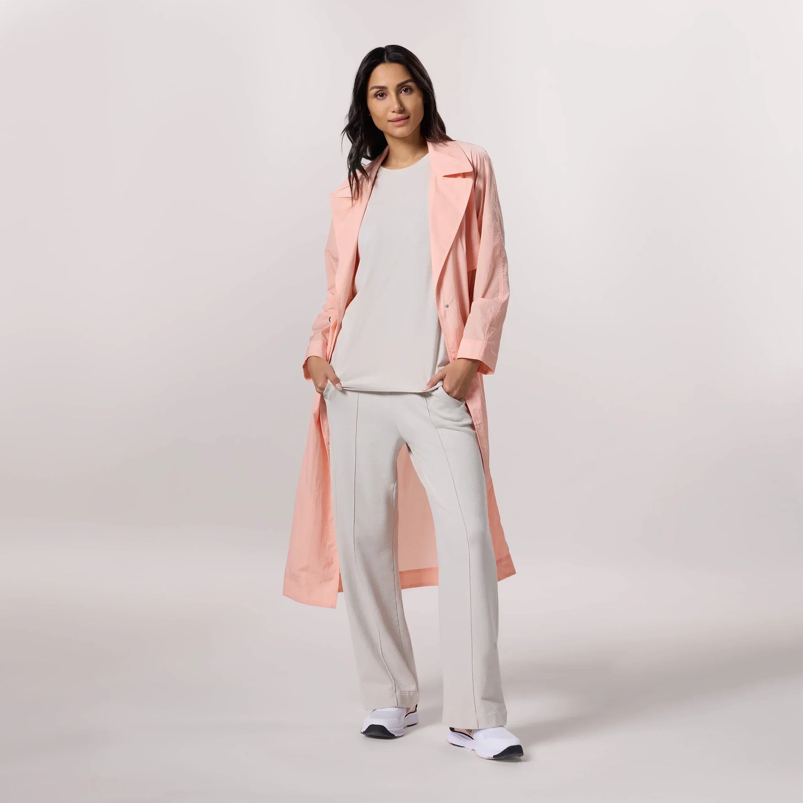 A model wearing a seasonal pink lightweight trench coat - عارضة أزياء ترتدي معطف وردي خفيف الوزن