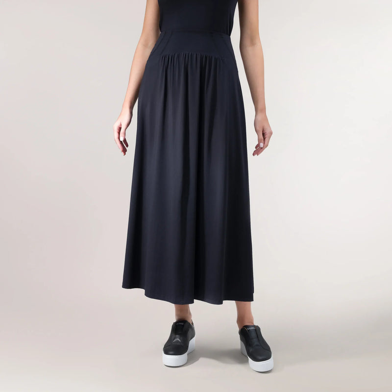A model wearing a black "Flow" jersey techno skirt with an athletic cut - عارضة أزياء ترتدي تنورة "فلو" من قماش الجيرسي باللون الأسود وبقصّة رياضية