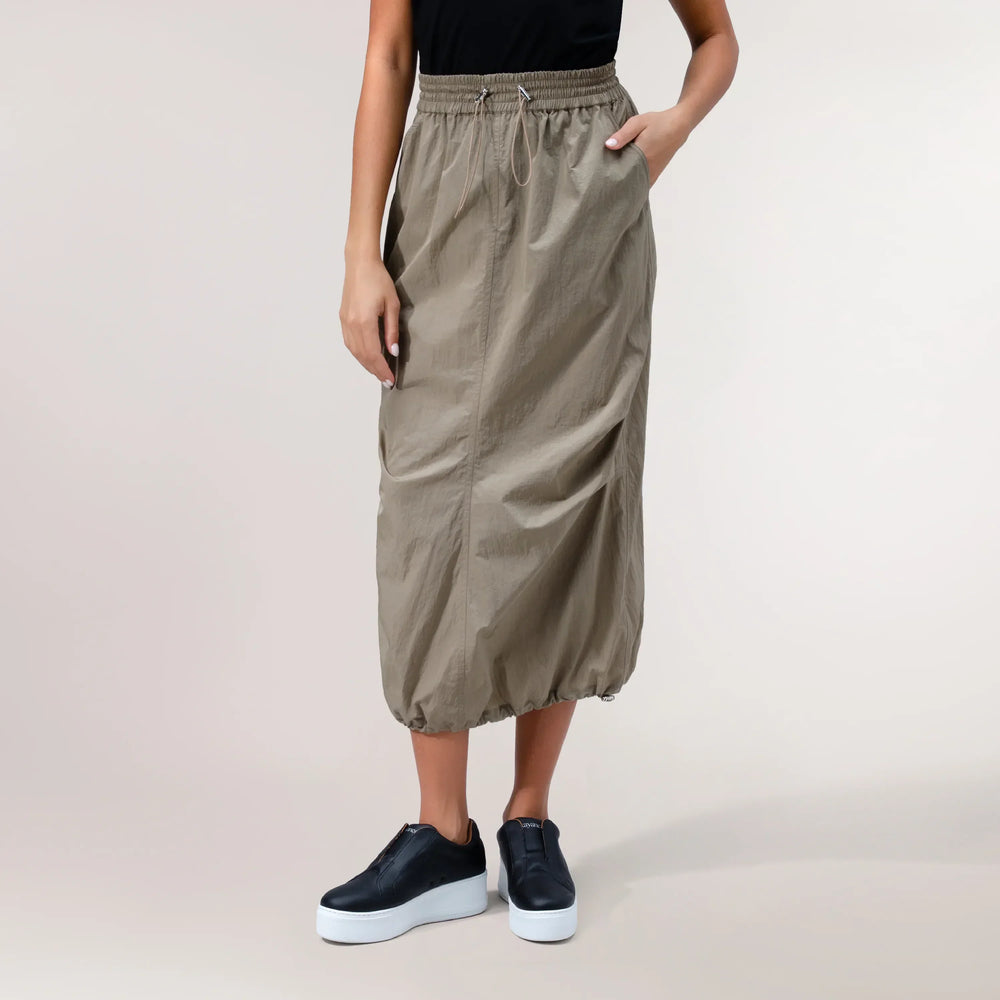 A model wearing a seasonal beige parachute skirt with pockets & elastic waistband - عارضة أزياء ترتدي تنورة باراشوت بيج مع جيوب وحزام مطاطي