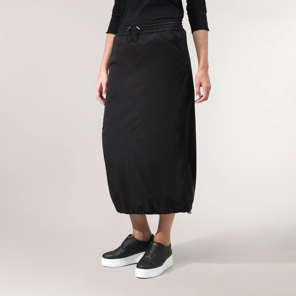 A model wearing seasonal black parachute skirt with waist adjustable band - عارضة أزياء ترتدي تنورة باراشوت سوداء مع حزام خصر قابل للتعديل