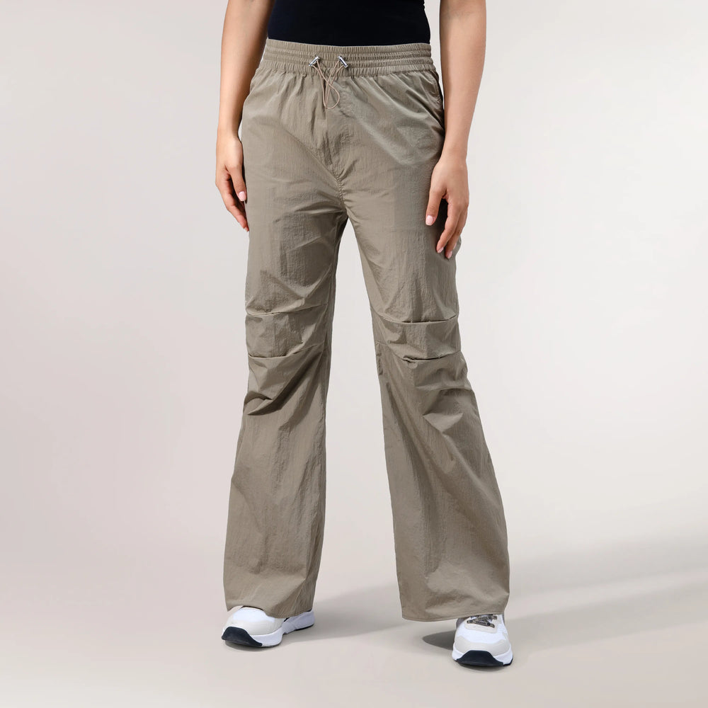 Beige parachute pants with adjustable cuffs with a lightweight drape - بنطال باراشوت بيج يتميز بحواف قابلة للتعديل وقماش خفيف ينسدل بنعومة