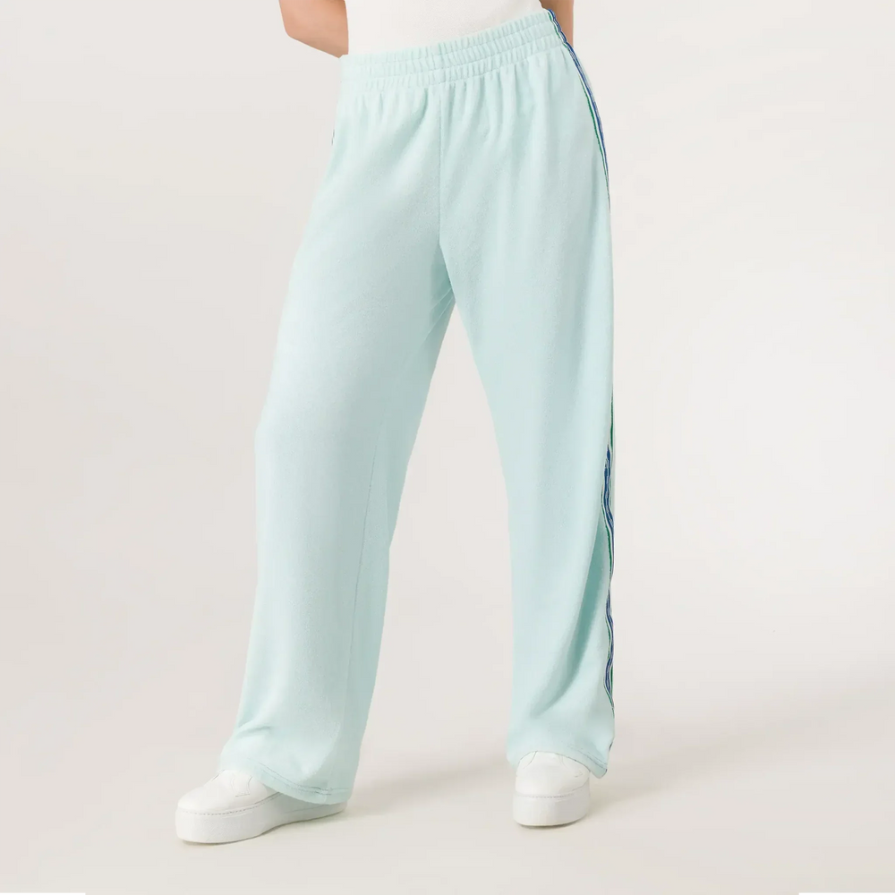 A model wearing a seasonal light blue velour track pants with side stripes - عارضة أزياء ترتدي بنطال رياضي باللون الأزرق فاتح مع خطوط جانبية