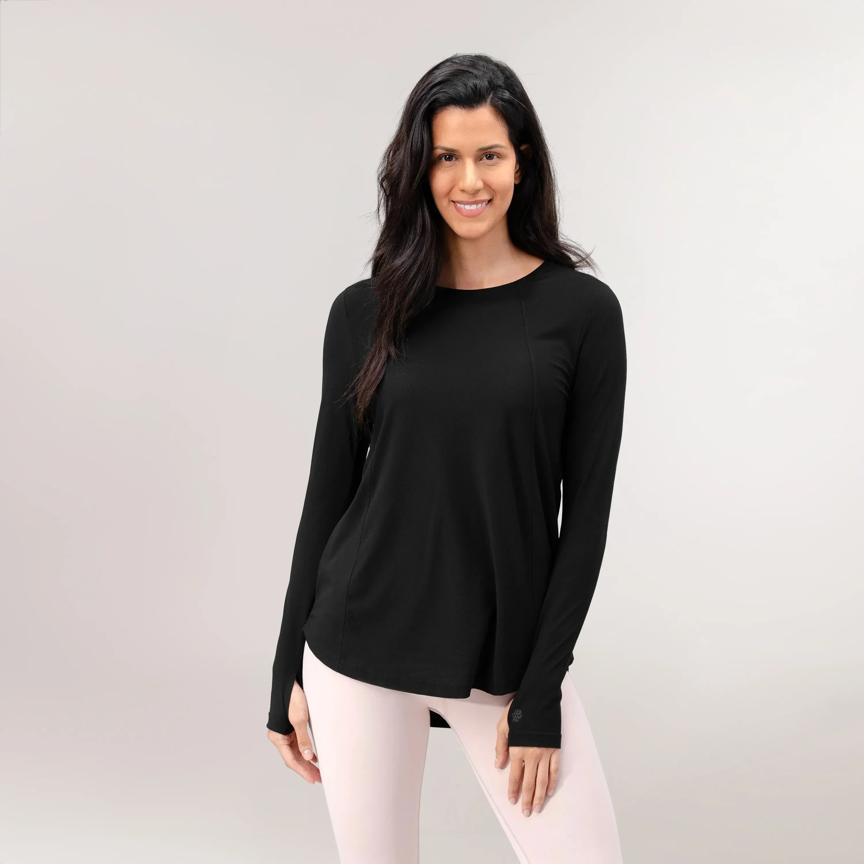 A model wearing a core black Twirl long sleeve top with thumb holes - عارضة أزياء ترتدي بلوزة "تويرل" سوداء بأكمام طويلة مزوّدة بفتحات للإبهام