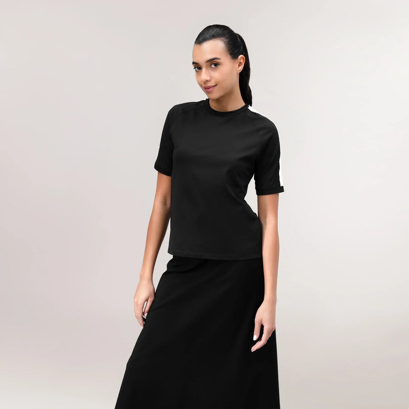 A model wearing a core black short sleeve tee over a matching skirt - عارضة أزياء ترتدي تيشيرت أسود بأكمام قصيرة فوق تنورة متناسقة